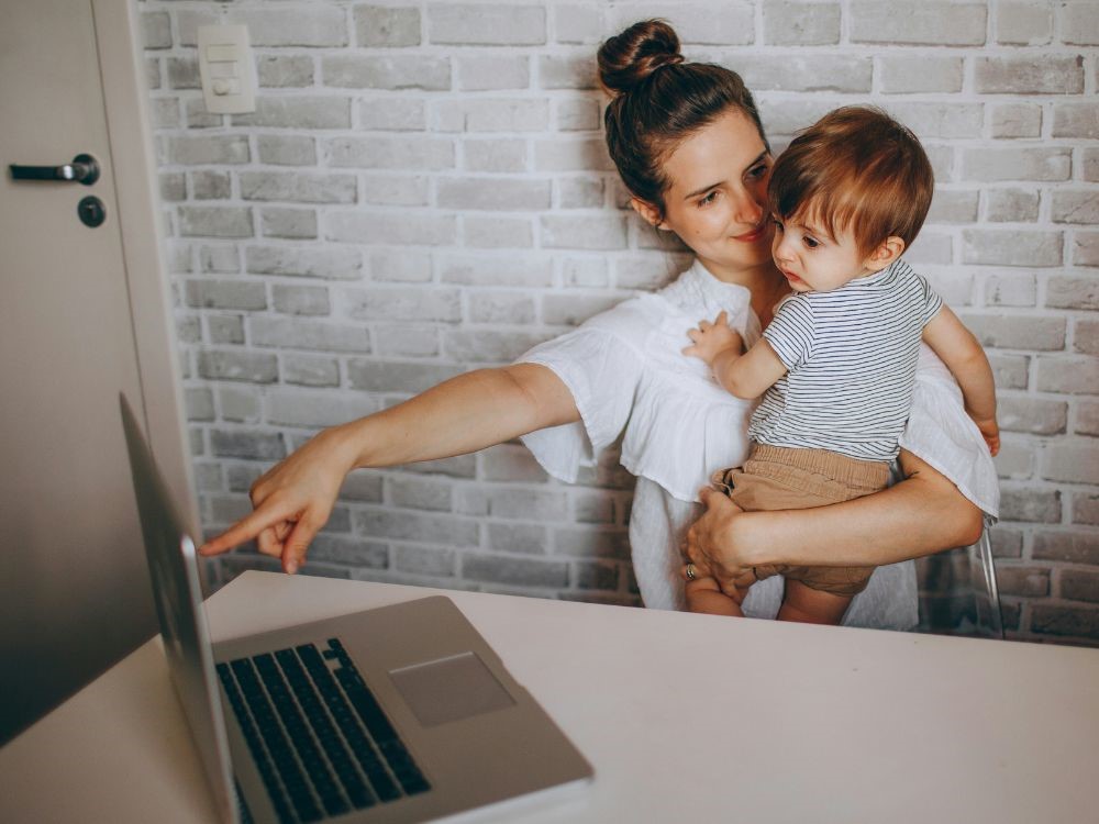 Sim nos mulheres somos multitarefas somos multitarefaz, nesta imagem mulher trabalha e cuida do filho ao mesmo tempo, mas em meio a todas as nossas tarefas temos sim que ter um tempo de  autocuidado para onosso  bem-estar feminino.