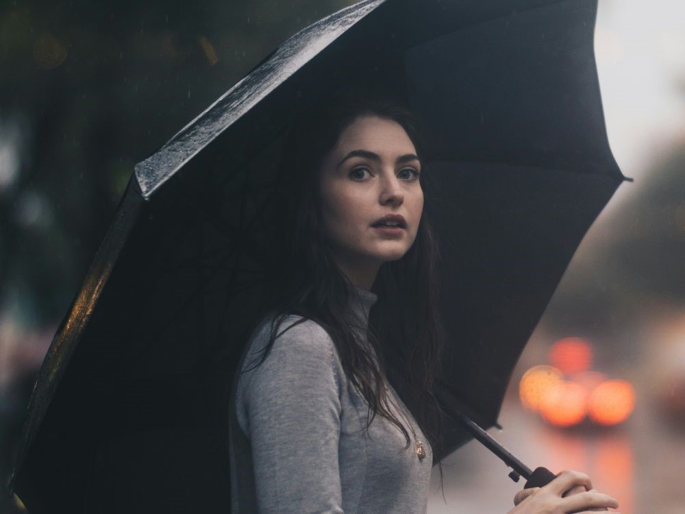 Conquiste praticidade e estilo no seu dia a dia verificando o clima do dia anterior. Nesta imagem uma mulher vestida e equipada adequadamente para um dia de chuva. Se organizar uma dia antes te ganrante isso 